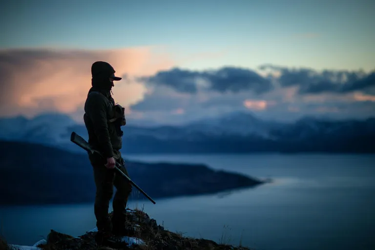 Outfitter standing in the field while the business runs in the background